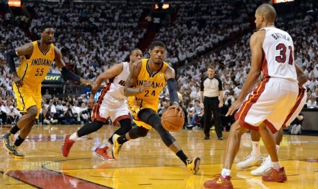 Forward Indiana Pacers, Paul George (tengah), mengontrol bola di tengah kepungan pemain Miami Heat dalam laga final Wilayah Timur babak playoff NBA pada Jumat (30/5). 