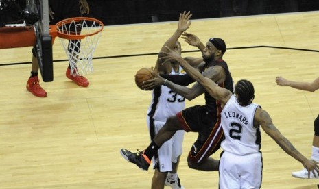 Forward Miami Heat, Lebron James (tengah), mencoba menjaringkan bola di tengah kepungan pemain San Antonio Spurs di laga final NBA 2014. 