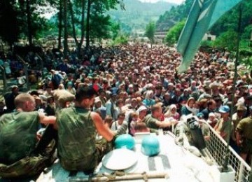 Foto pada 13 Juli 1995, tampak dua tentara Pasukan PBB asal Belanda duduk di atas APC melihat warga Muslim Srebenica berkumpul di desa Potomari sebelum digiring oleh tentara Serbia.