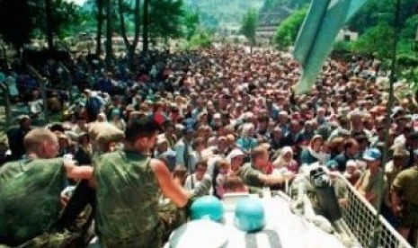 Foto pada 13 Juli 1995, tampak dua tentara Pasukan PBB asal Belanda duduk di atas APC melihat warga Muslim Srebenica berkumpul di desa Potomari sebelum digiring oleh tentara Serbia.