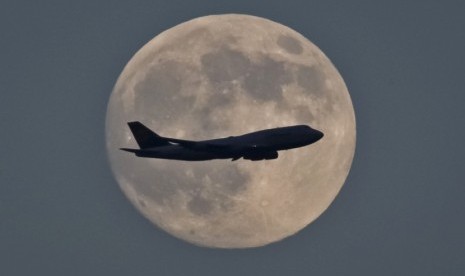  Foto siluet pesawat terbang melintas di udara dengan latar bulan purnama di Frankfurt. (EPA/Mumpenhorst) 