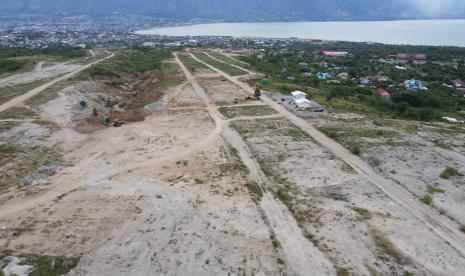 Foto udara alat berat dan truk dioperasikan di lokasi pekerjaan pembangunan infrastruktur kawasan pemukiman hunian tetap Talise di Kelurahan Talise di Palu, Sulawesi Tengah. Menteri PUPR Basuki sebut semua proyek infrastruktur selesai pada semester 1 2024.