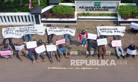 Foto udara sejumlah pengunjuk rasa membawa poster saat aksi damai usut tuntas pemotongan dana Bantuan Sosial Tunai (BST) di depan kantor Kejaksaaan Negeri, Karawang, Jawa Barat, Senin (30/8/2021). Aksi tersebut menuntut KPK dan Kemensos menangani kasus pemotongan dana Bantuan Sosial Tunai (BST) 281 warga Karawang yang tadinya Rp600 ribu menjadi Rp300 ribu. 