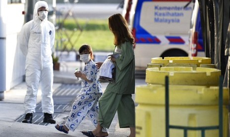 Foto yang dirilis Pemerintah Malaysia menunjukkan dua orang warga negara Malaysia yang baru tiba dari Wuhan di Bandara Internasional Kuala Lumpur (KLIA), Sepang, Rabu (26/2). Pemerintah Malaysia menjemput warganya dari Wuhan pada Selasa (25/2).