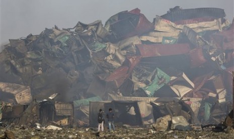 Fotografer berada di dekat sisa-sisa peti kemas yang hancur akibat ledakan di sebuah gudang di Kota Tianjin, Kamis (13/8). 