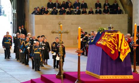 Fotografer dan wartawan dapat dilihat di latar belakang, kanan atas, dengan peti mati Ratu Elizabeth II di katafalque di Westminster Hall, London, Rabu 14 September 2022. Rencana oleh organisasi berita yang telah ada selama bertahun-tahun — bahkan puluhan tahun — untuk menutupi kematian Ratu Elizabeth II terpicu dan diuji saat peristiwa itu berlangsung. London telah dibanjiri wartawan, dengan lebih banyak lagi yang menuju ke kota untuk menghadiri upacara pemakaman pada hari Senin.