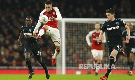 Francis Coquelin (tengah) membuang bola dari kejaran pemain West Ham United, Declan Rice, (kanan) pada babak perempatfinal English League Cup  di  Emirates stadium, London,