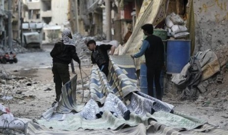 Free Syrian Army fighters pull carpets along a rubble-filled street as they prepare to use them as curtains to provide cover from snipers loyal to Syria's President Bashar al-Assad in Deir al-Zor, eastern Syria February 11, 2014.