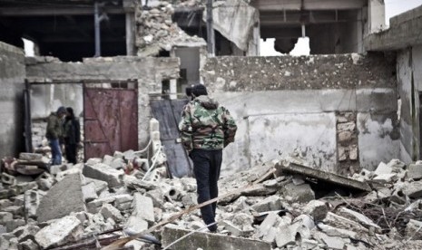 Free Syrian Army fighters walk amid the ruins of a village situated a short distance from an area where fighting between rebels and government forces continues, Saturday, Dec. 22, 2012.  