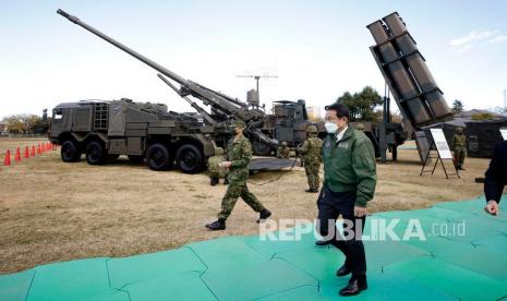  Fumio Kishida, Perdana Menteri Jepang, berjalan melewati Japan Ground Self-Defense Force (JGSDF) tipe 19 155 mm self-propelled howitzer (belakang, L) dan rudal permukaan-ke-kapal Tipe 12 (belakang, R), sebagai dia memeriksa peralatan selama peninjauan di JGSDF Camp Asaka di Tokyo, Jepang, Sabtu (27/11).