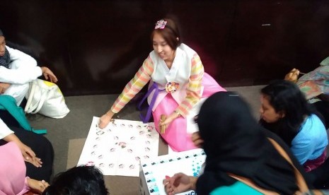 Gadis Korea menunjukkan cara bermain yut nori, salah satu permainan tradisional negaranya 