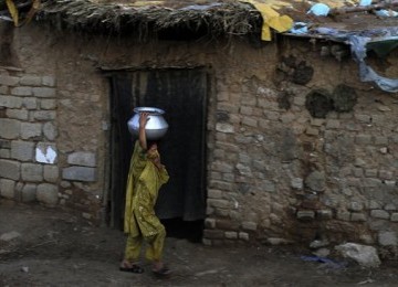 Gadis Pakistan yang mengungsi dari kawasan tribal yang dilanda pertempuran, tengah mengambil air dari sebuah sumur di kawasan kumuh Islamabad.