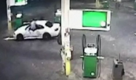 Gambar dari CCTV yang menunjukkan si pemilik mobil lompat masuk ke dalam jendela mobil untuk menghalau pencuri yang membawa mobilnya.