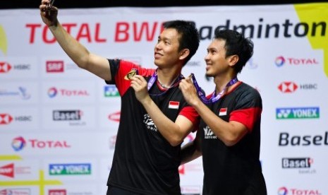 Ganda putra Indonesia Hendra Setiawan (kiri) dan Mohammad Ahsan berswafoto dengan menunjukan medali emas saat prosesi penyerahan medali pada Kejuaraan Dunia Bulu Tangkis 2019 di St. Jakobshalle, Basel, Swiss, Ahad (25/8/2019).  