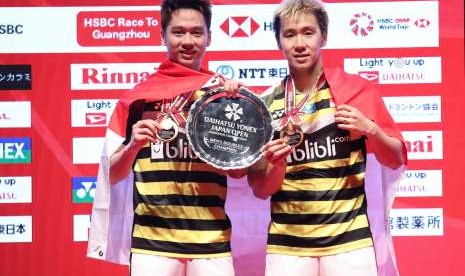 Ganda putra Indonesia Kevin Sanjaya Sukamuljo (kiri) dan Marcus Fernaldi Gideon (kanan) menunjukkan medali dan trofi juara seusai pertandingan babak final Japan Open 2018 melawan pasangan Cina Li Junhui/Liu Yuchen di Tokyo, Jepang, Minggu (16/9). 