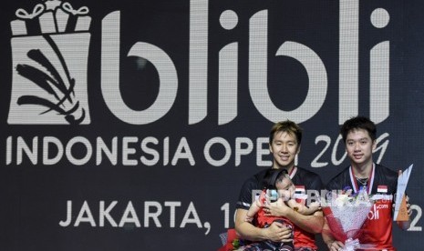 Ganda putra Indonesia Marcus Fernaldi Gideon (kiri) dan Kevin Sanjaya Sukamuljo menunjukan piala di atas podium usai bertanding mengalahkan ganda putra Indonesia Mohammad Ahsan dan Hendra Setiawan pada final Blibli Indonesia Open 2019 di Istora Gelora Bung Karno, Jakarta, Ahad (21/7/2019).