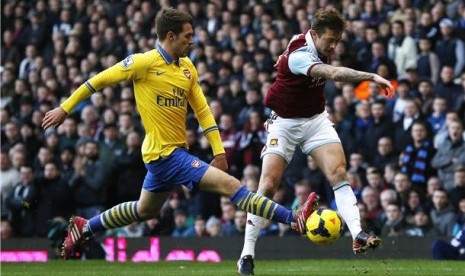 Gelandang Arsenal, Aaron Ramsey, menghadang pergerakan pemain West Ham United, George McCartney, dalam laga Liga Primer Inggris di Upton Park, London, Kamis (26/12). 