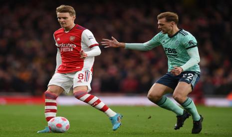 Gelandang Arsenal Martin Odegaard (kiri) mengawal bola di tengah adangan pemain Leicester Kiernan Dewsbury-Hall saat kedua tim bentrok pada lanjutan Liga Primer Inggris, Senin (14/3/2022).