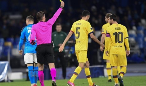 Gelandang Barcelona Sergio Busquets (tengah) menerima kartu kuning saat melawan Napoli. Barcelona ditahan imbang Napoli 1-1 pada leg pertama babak 16 besar Liga Champions.