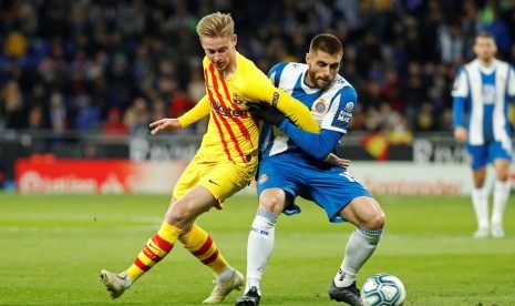 Gelandang Espanyol David Lopez (kanan) berebut bola dengan gelandang Barcelona Frankie De Jong. Lopez mencetak gol Espanyol ke gawang Barcelona di Stadion RCDE, Barcelona, Ahad (5/1) dini hari WIB.