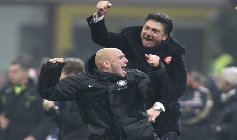 Gelandang Inter Milan asal Argentina Esteban Cambiasso (bawah) dan pelatih Inter Milan Walter Mazzarri merayakan kemenangan usai mengalahkan AC Milan pada pertandingan Serie A di stadion San Siro, Milan, Ahad (22/12).   (AP/Antonio Calanni)