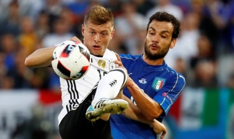 Gelandang Jerman Toni Kroos (kiri) berebut bola dengan gelandang Italia Marco Parolo.