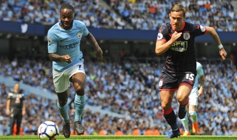 Gelandang Manchester City, Raheem Sterling (kiri) menggiring bola dibayangi oleh bek Huddersfield, Chris Lowe pada laga Liga Primer di Stadion Etihad, Ahad (6/5). Laga berakhir imbang tanpa gol.