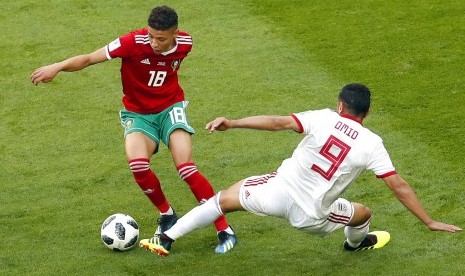 Gelandang Maroko, Amine Harit (kiri) coba diadang oleh pemain Iran, Omid Ebrahimi pada laga Grup B Piala Dunia 2018, di Stadion St Petersburg, Rusia, Jumat (15/6). 