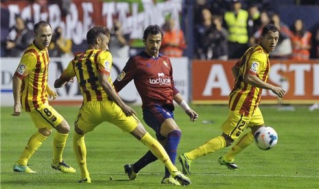 Gelandang Osasuna, Miguel Angel de las Cuevas (dua kanan), berusaha melepaskan diri dari kepungan pemain Barcelona dalam laga La Liga di Stadion El Sadar, Pamplona, Sabtu (19/10). 