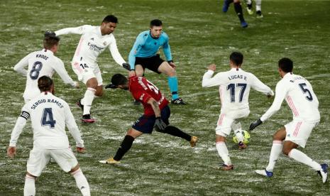 Gelandang Osasuna, Ruben Garcia (tengah), dikepung pemain Real Madrid dalam laga La Liga Spanyol yang bersalju di Stadion El Sadar, Pamplona, Sabtu (9/1). Real Madrid gagal menggeser Osasuna dari puncak klasemen.