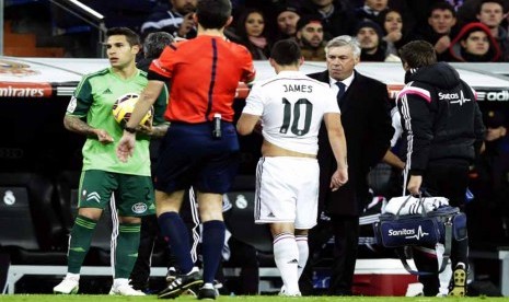 Gelandang Real Madrid, James Rodriguez (tengah), ditarik keluar lapangan akibat mengalami cedera saat menghadapi Celta Vigo dalam laga La Liga Spanyol di Santiago Bernabeu, Madrid, Sabtu (6/12). 