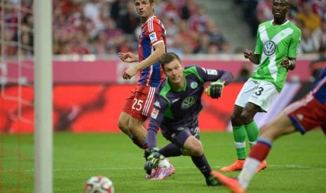 Gelandang serang Bayern Muenchen, Thomas Mueller (kiri), menjebol gawang VfL Wolfsburg dalam laga pembuka kompetisi Bundesliga Jerman di Muenchen, Jerman, Jumat (22/8). 