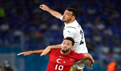 Gelandang Timnas Turki, Hakan Calhanoglu (bawah), berebut bola dengan pemain Itali, Alessandro Florenzi, dalam laga Grup A Euro 2020 di Stadion Olimpico, Roma, Jumat (11/6).