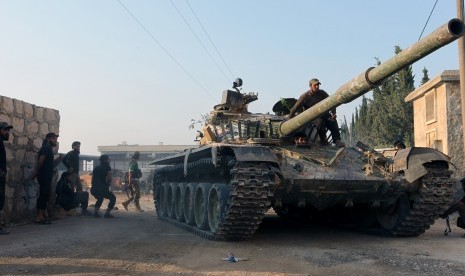 Gerilyawan menaiki kendaraan tank di kawasan Aleppo, Suriah.