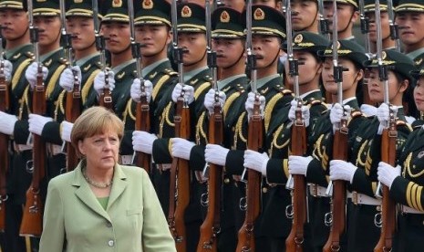 Germany's Chancellor Angela Merkel reviews an honour guard during a welcoming ceremony outside the Great Hall of the People in Beijing July 7, 2014.