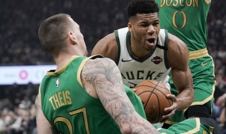 Bintang Milwaukee Bucks Giannis Antetokounmpo (tengah) mempertahankan bola dari pemain Boston Celtics dalam lanjutan kompetisi NBA.