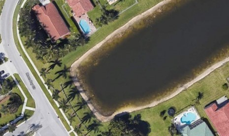 Google Earth memperlihatkan adanya sedan putih yang tercebur di tepi kolam besar di Moon Bay, Wellington, Florida, AS.