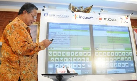 Governor of Bank Indonesia, Darmin Nasution, demonstrates how to use e-money system. Three biggest telecommunication operators in Indonesia collaborate to provide e-money service using short message service (SMS).  