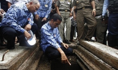 Governor of Jakarta Joko Widodo (center-front) checks teh semage system in MH Thamrin Street in Central Jakarta on Wednesday after the earlier rains inundate the street.   