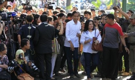 Governor of Jakarta who also a presidential candidate from the Indonesian Democratic Party for Struggle (PDIP) party, Joko Widodo, and his wife Iriana (both in white) arrive to vote in the parliamentary elections, at a polling station in Jakarta April 9, 2