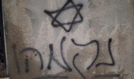 Grafiti bintang daud yang tertera di dinding rumah warga Palestina yang terbakar di Duma, dekat Nablus, Jumat (31/7).