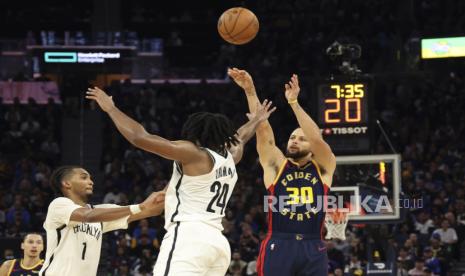 Guard Golden State Warriors Stephen Curry melepaskan tembakan melewati guard Brooklyn Nets Cam Thomas dalam pertandingan bola basket NBA di San Francisco, Senin, 25 November 2024. 