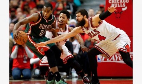 Guard Milwaukee Bucks Khris Middleton (kiri) berusaha menjaga bola dari guard Chicago Bulls Derrick Rose (tengah) dalam lanjutan play-off NBA.