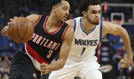 Guard Portland Trail Blazers, CJ McCollum (kiri) ditempel oleh guard Minnesota Timberwolves, Tyus Jones pada laga lanjutan kompetisi NBA, di Minneapolis, Senin (3/4).