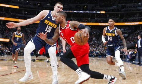 Guard Portland Trail Blazers guard Damian Lillard membawa bola berusaha melewati center Denver Nuggets Nikola Jokic dan guard Gary Harris dalam pertandingan NBA, Rabu (5/2) WIB. 