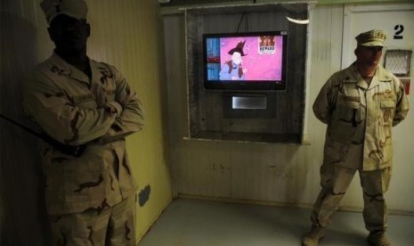 Guards stand next to a television showing a cartoon as journalists visit the movie room at the Camp Four detention facility at the U.S. Naval Station Guantanamo Bay December 10, 2008.