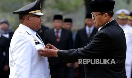 Gubernur Banten Wahidin Halim (kanan) menyematkan tanda jabatan saat melantik Penjabat (Pj) Wali Kota Serang Ade Aryanto (kiri) di Serang, Rabu (3/10).