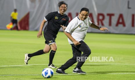 Gubernur DKI Jakarta Anies Baswedan (kanan) berusaha melewati hadangan pesepak bola tim DPRD DKI Jakarta saat uji coba lapangan latih di Jakarta International Stadium, (JIS) di Tanjung Priok, Jakarta Utara, Kamis (28/10/2021). Pertandingan persahabatan yang digelar PT Jakarta Propertindo (Jakpro) Perseroda tersebut adalah bagian langkah pembuktian bahwa dua lapangan latih JIS yang berstandar internasional kini sudah bisa dimanfaatkan untuk berbagai kegiatan masyarakat. 