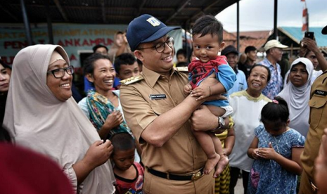 Gubernur DKI Jakarta, Anies Baswedan menggendong seorang anak bernama Anies Sandi di Kampung Akuarium, Jakarta, Selasa (28/11).