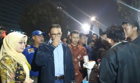 Gubernur DKI Jakarta, Anies Baswedan menikmati kopi yang dibeli dari pedagang kopi keliling, Ahad (31/12).